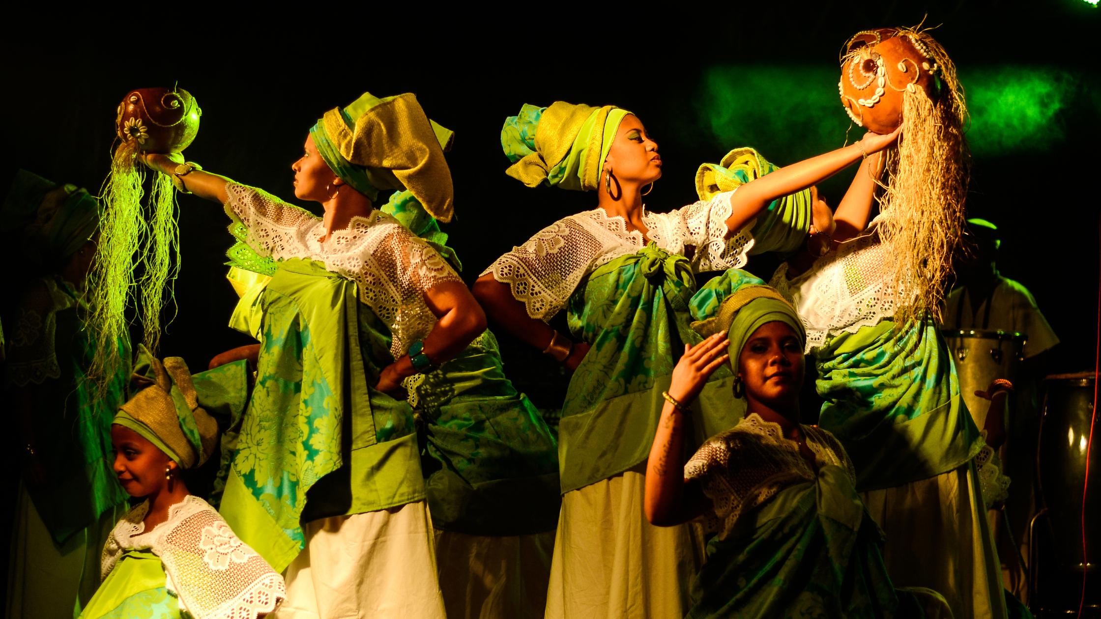 African women in traditional cultural garb performing a song and dance.