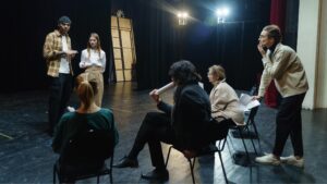 A group of actors at a theatre audition having a meeting on the stage.