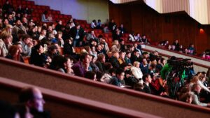 Large audience in a theatre watching a performance.